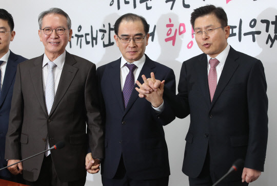 태영호(가운데) 전 주영 북한대사관 공사가 11일 국회에서 자유한국당 입당과 4·15 총선 지역구 후보 출마 발표 기자회견 후 황교안(오른쪽) 대표와 손을 잡고 있다. 왼쪽은 김형오 공천관리위원장.  연합뉴스